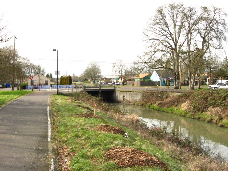 a narrow road running past an overpass and river