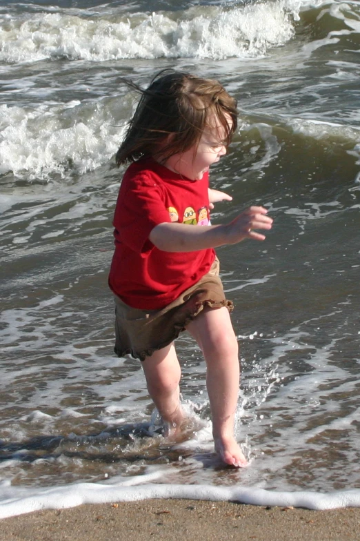 a little girl walking in the water at the beach