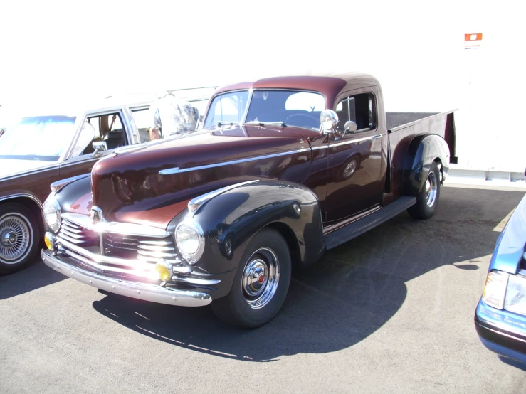 two old, shiny, classic trucks parked in a lot