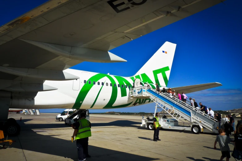 an airplane sits with people boarding it, and the bottom part has been taken down