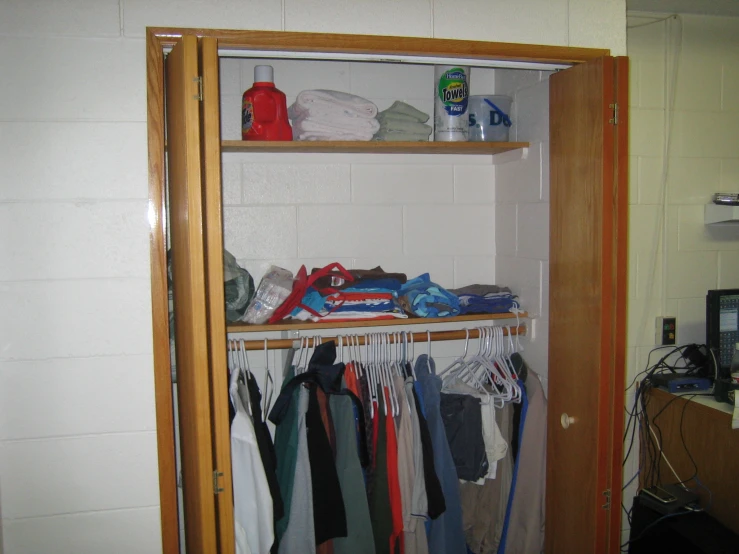 a white shelf filled with various shirt pieces and clothes