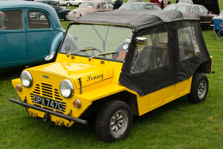 a yellow car is on some grass near a blue truck