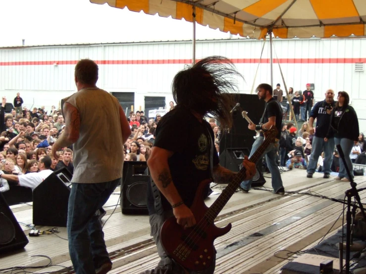 two people on stage playing guitars as a band looks on