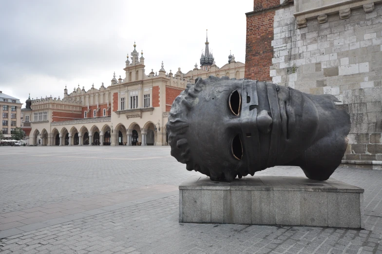 a large face sculpture in front of a brick building