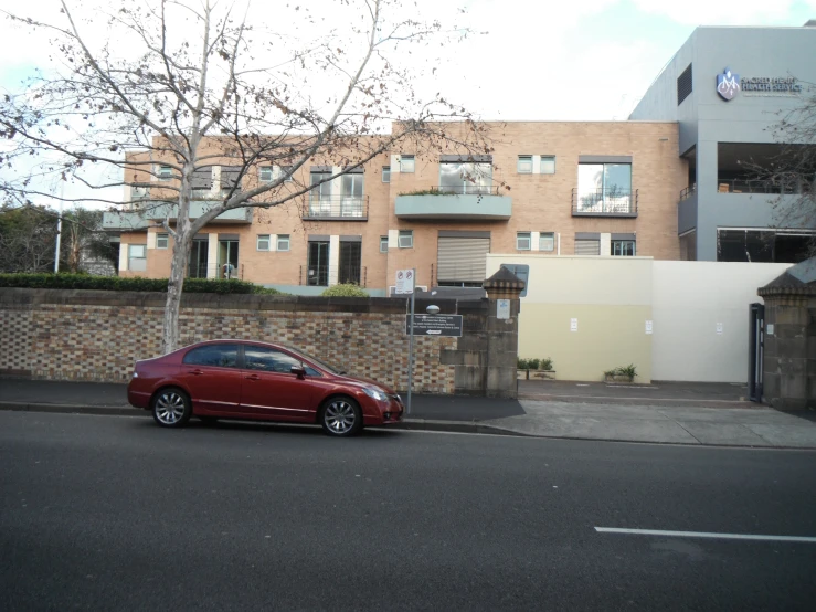 a red car parked on the street next to a tree