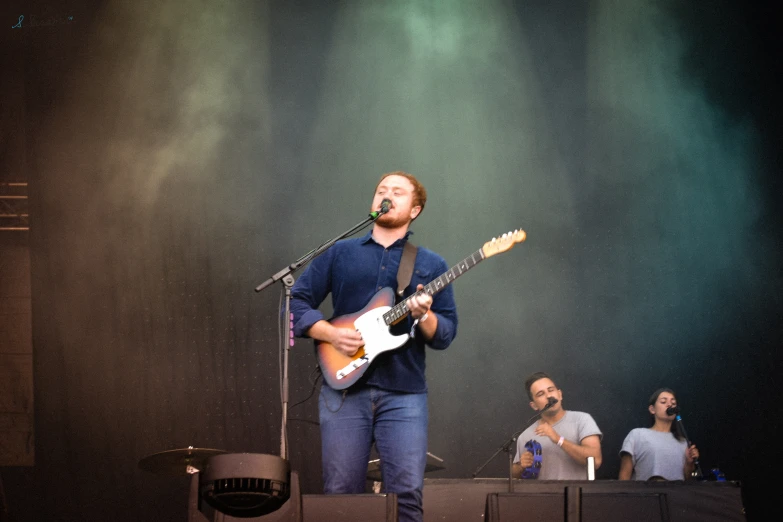 a man singing on stage and playing guitar