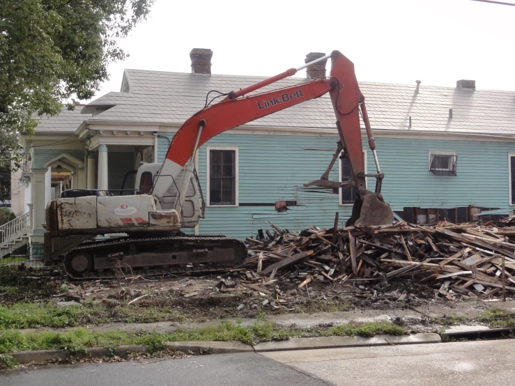 a crane working in front of a house with rubble