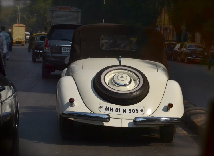 an old white car on the street in traffic