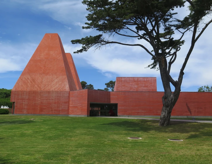 a tall red brick building sitting on top of a lush green field