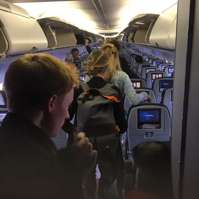 people sit inside an airplane looking at their electronics