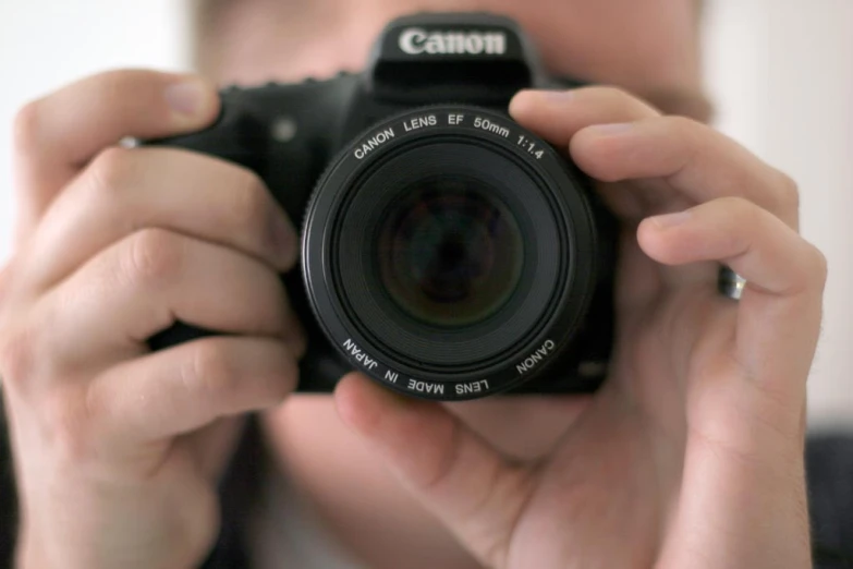 the pographer's camera lens is pointed upwards to show off the small, white text underneath the lens