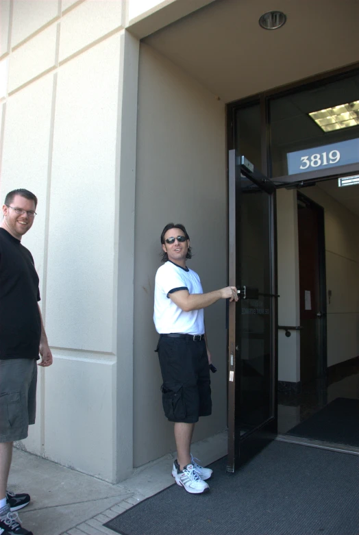 two guys holding up the door to a large building