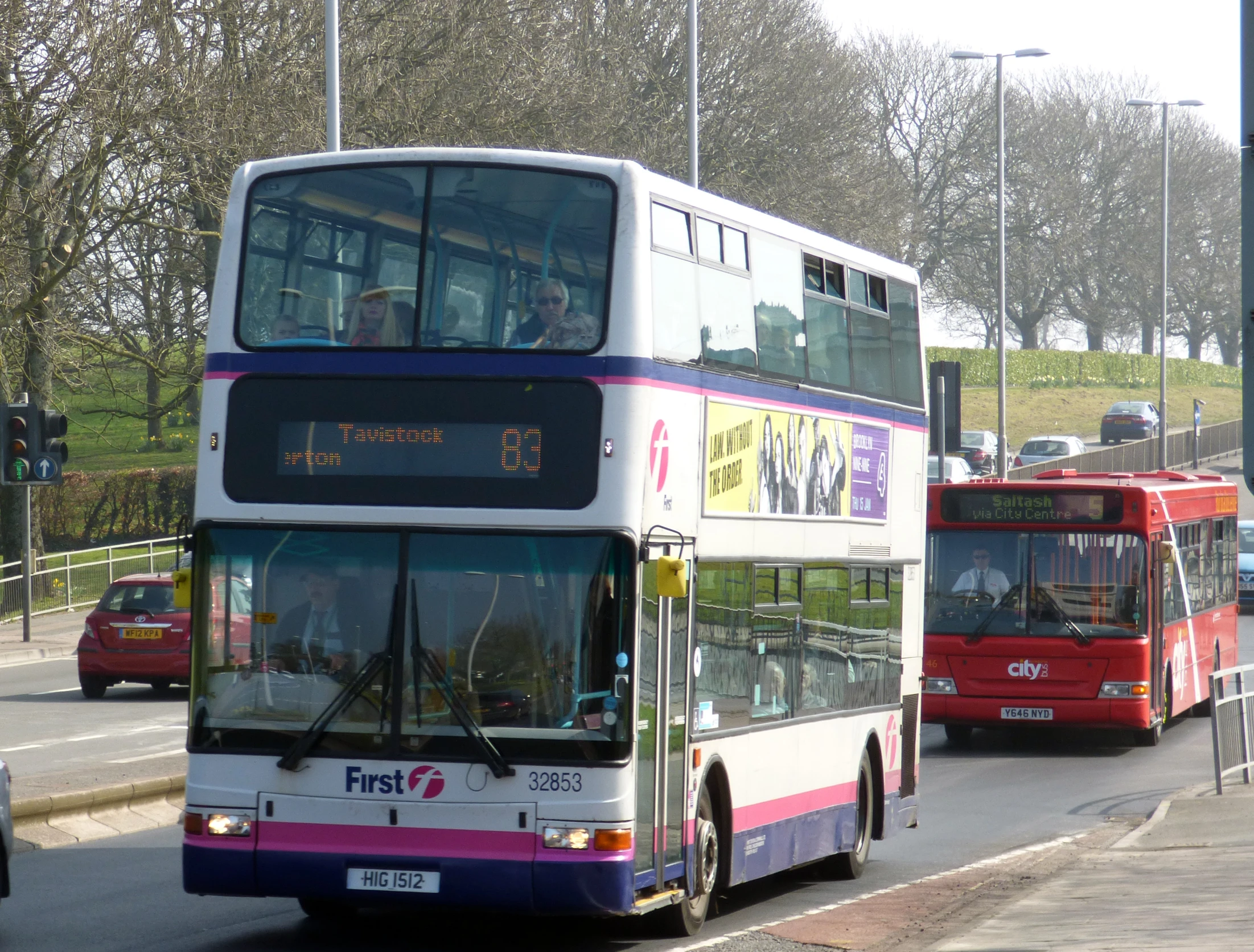 two double decker buses pass a bus stop