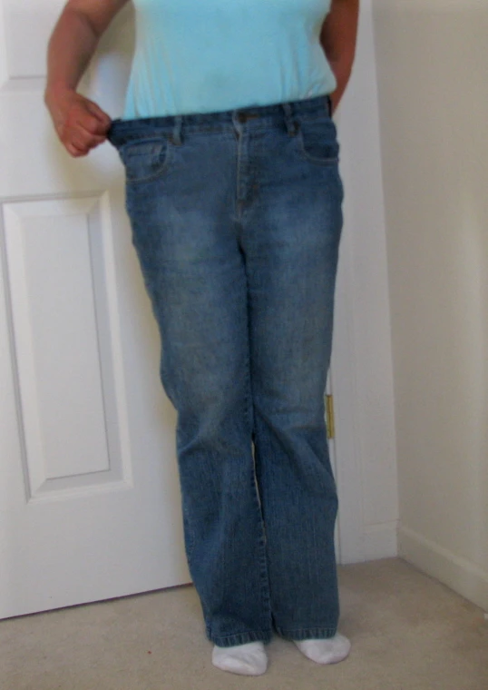 a woman stands in front of a door, wearing blue and wearing white shoes