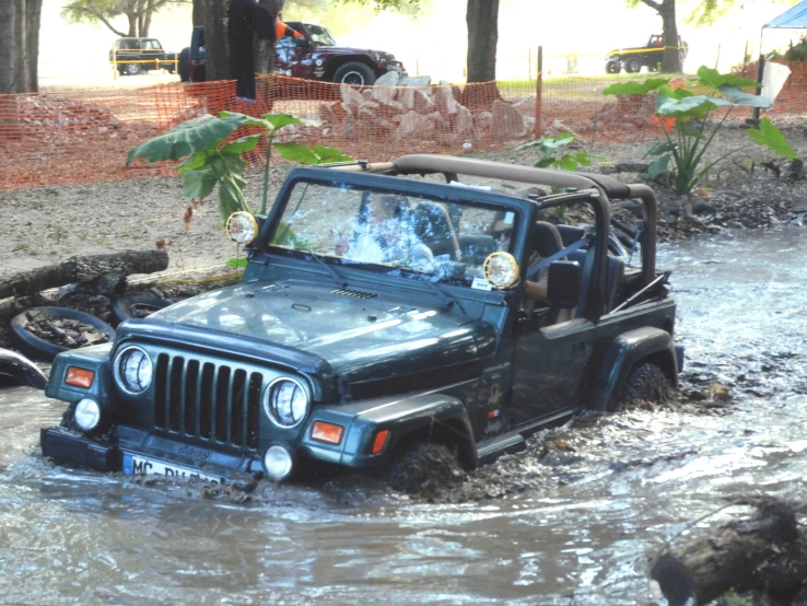 a jeep is stuck in water and the driver is riding in it