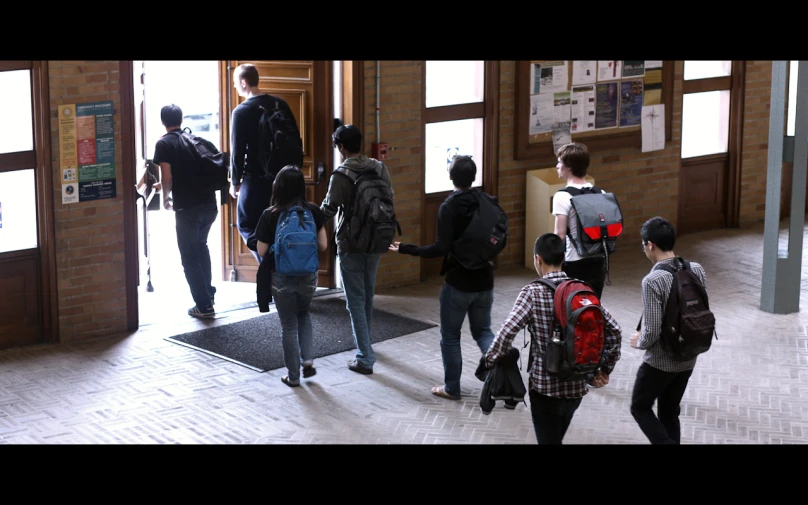 several young people walking through a school hallway