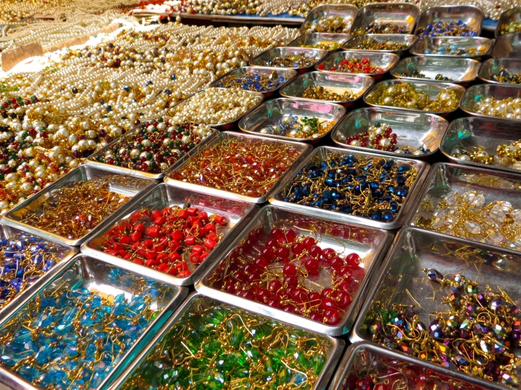 a bunch of containers are filled with many different colored beads