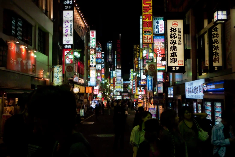 people are walking down an urban street in the dark