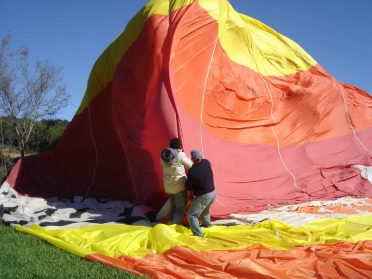 a man fixing the cover on a large colorful kite