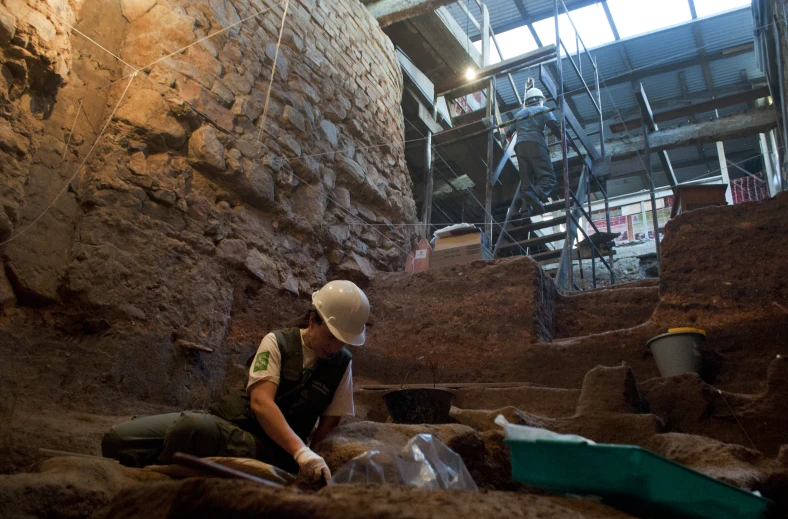 a person in hard hat and vest with other men working in an indoor area