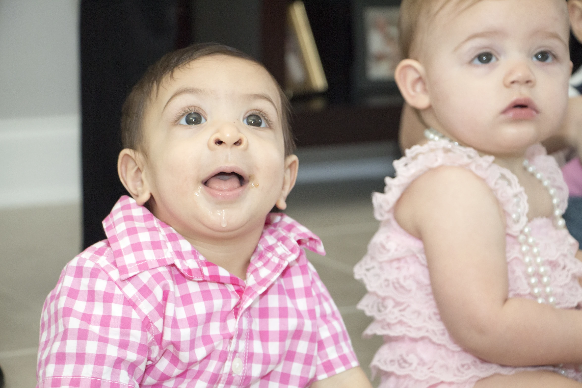 a baby girl and boy sit on the floor