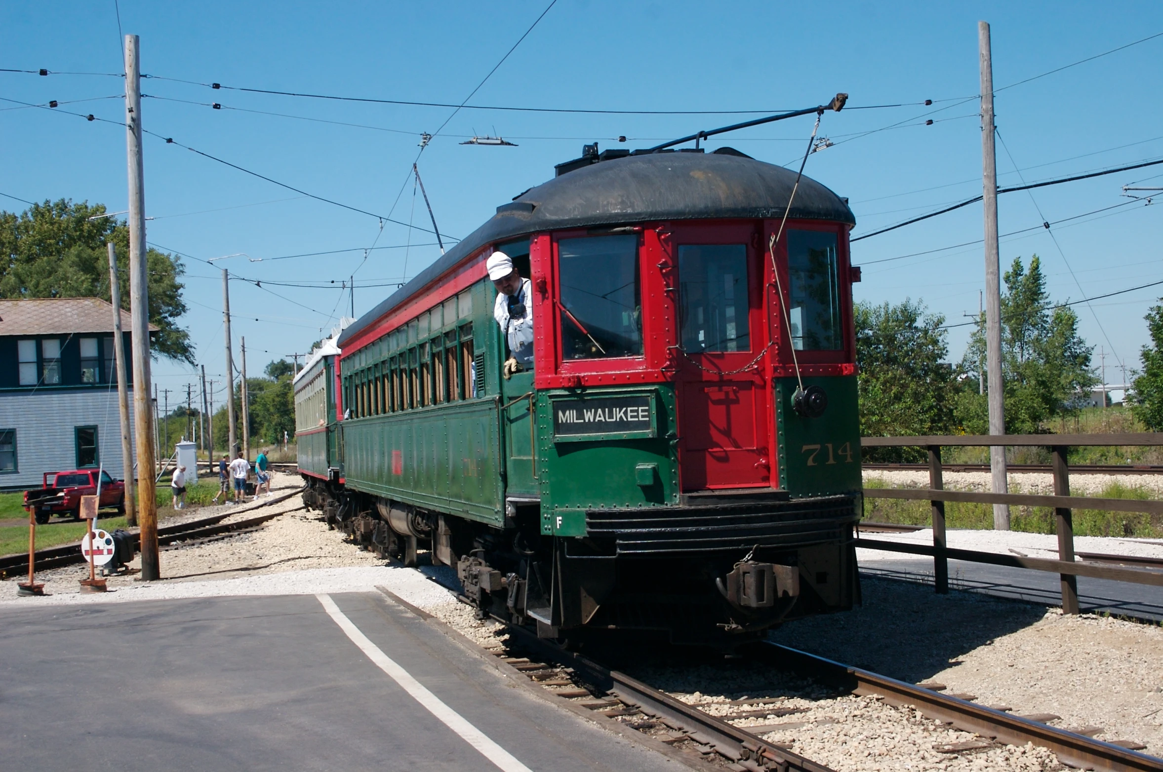 a green train sits on a track near the street