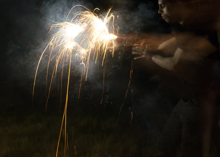 a person watching another fireworks burn brightly