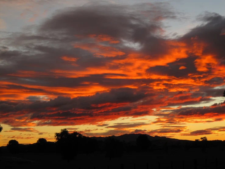 a bright orange sunset is seen through the clouds