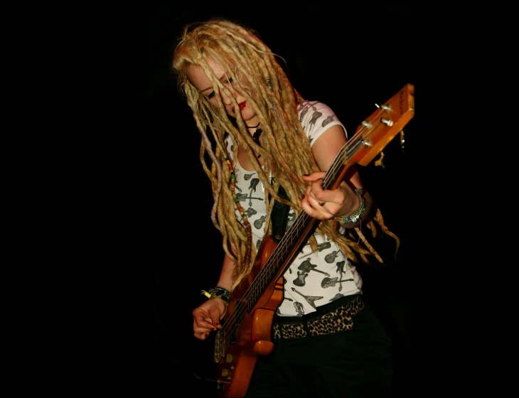 a blonde female with dread locks holding an electric guitar