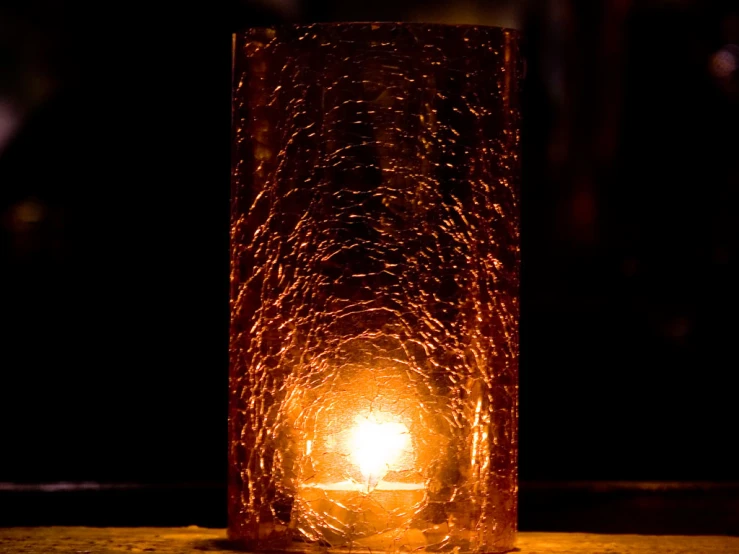 a candle lit up with an intricate design in a cylinder shape