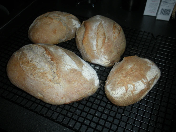 a group of three loaves of bread on a black rack