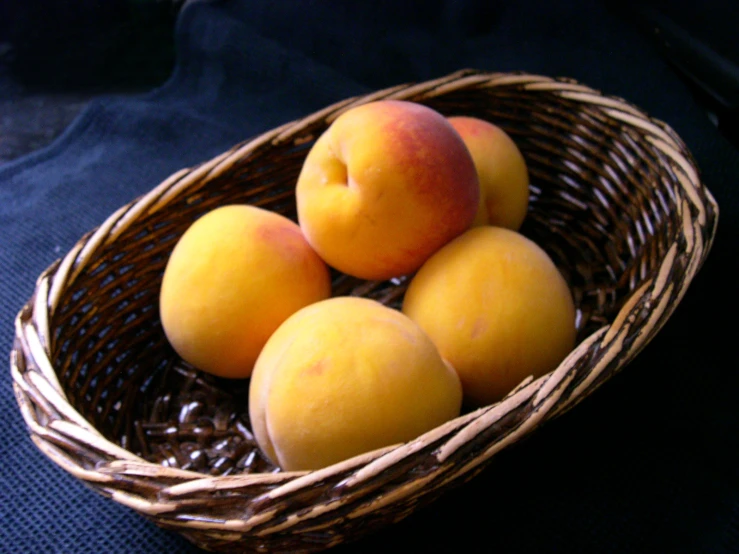 four apricots sit in a wicker bowl