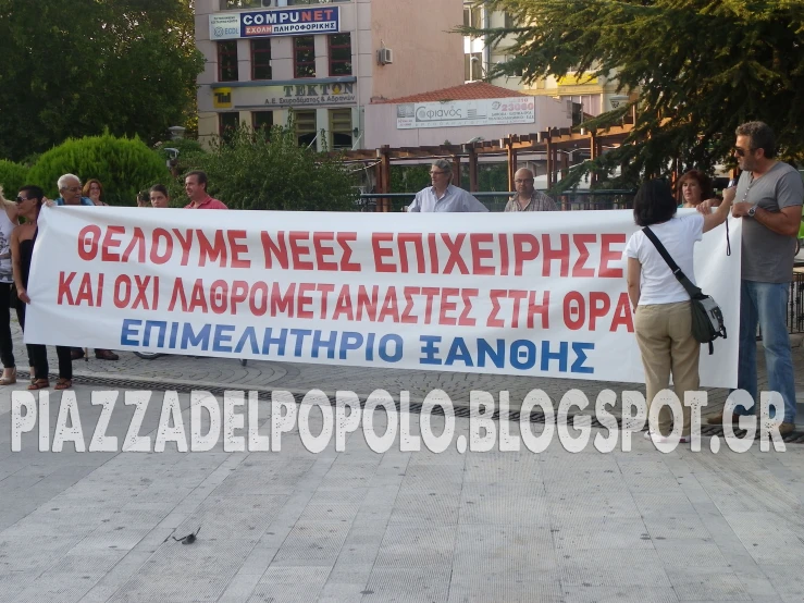 two people holding up a banner with writing in multiple languages