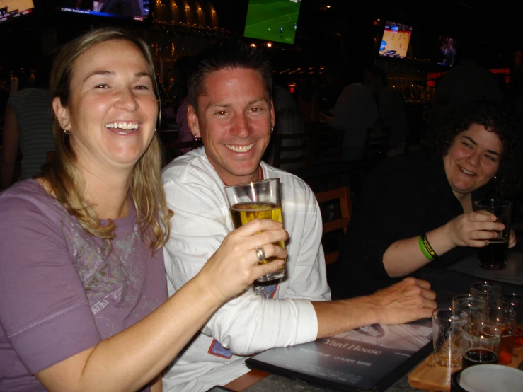 the man and woman are posing for the camera, having drinks