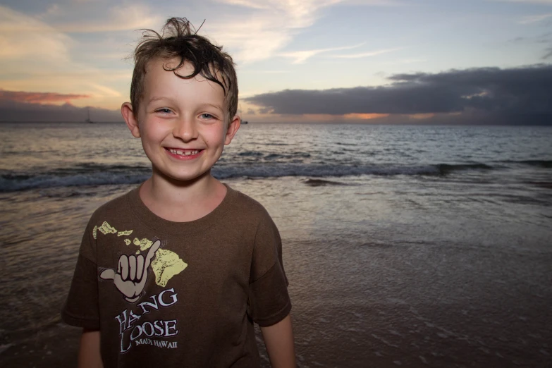 a  poses on the beach with a sunset in the background