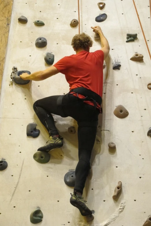 man practicing climbing on the wall with climbing gear