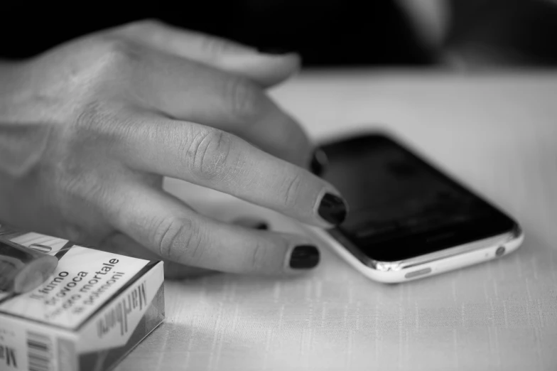 black and white pograph of person's hands using cellphone