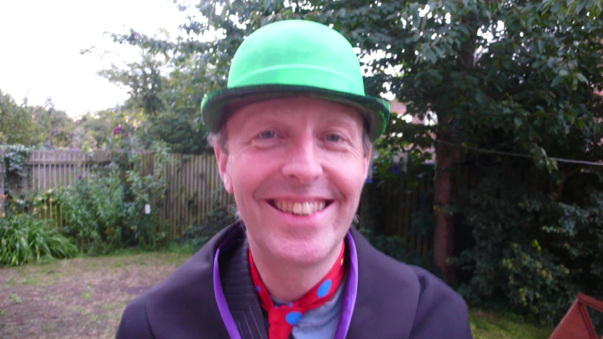 a man smiling at the camera wearing a green hat and medal