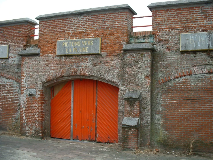 the red doors are closed by the brick wall