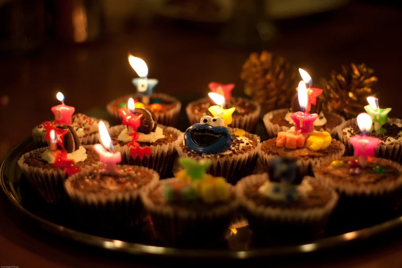 many cup cakes with candles on top of them