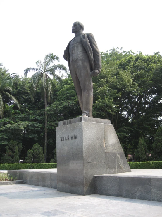 a statue of a man with a suit is in the middle of the park