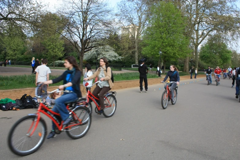 three people riding bicycles down the street, surrounded by pedestrians