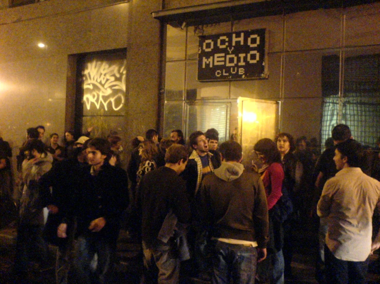 large group of people standing around a crowd outside of a building