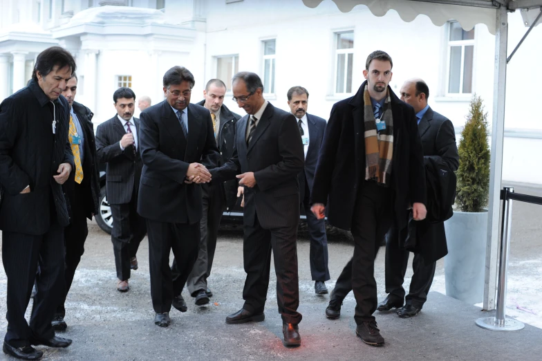 four men standing and greeting each other outside