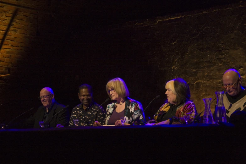 five people are at a table on a stage