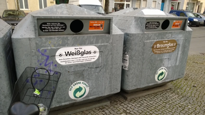 two gray garbage bins with metal wire baskets on them