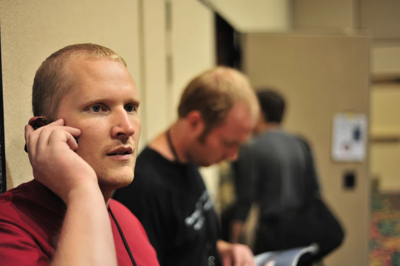 two men talking on cellphones next to each other