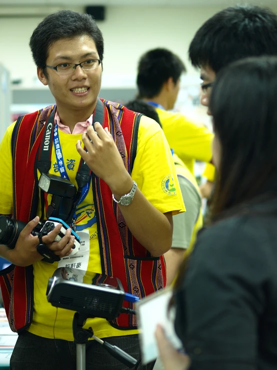 two people looking at a cell phone while one person is holding a camera