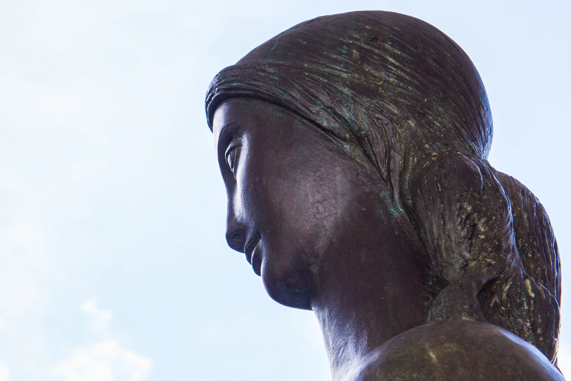 the profile of a bronze statue has a headscarf on it