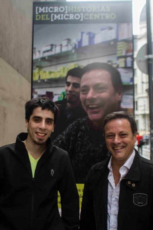 two men posing for a picture in front of a movie poster